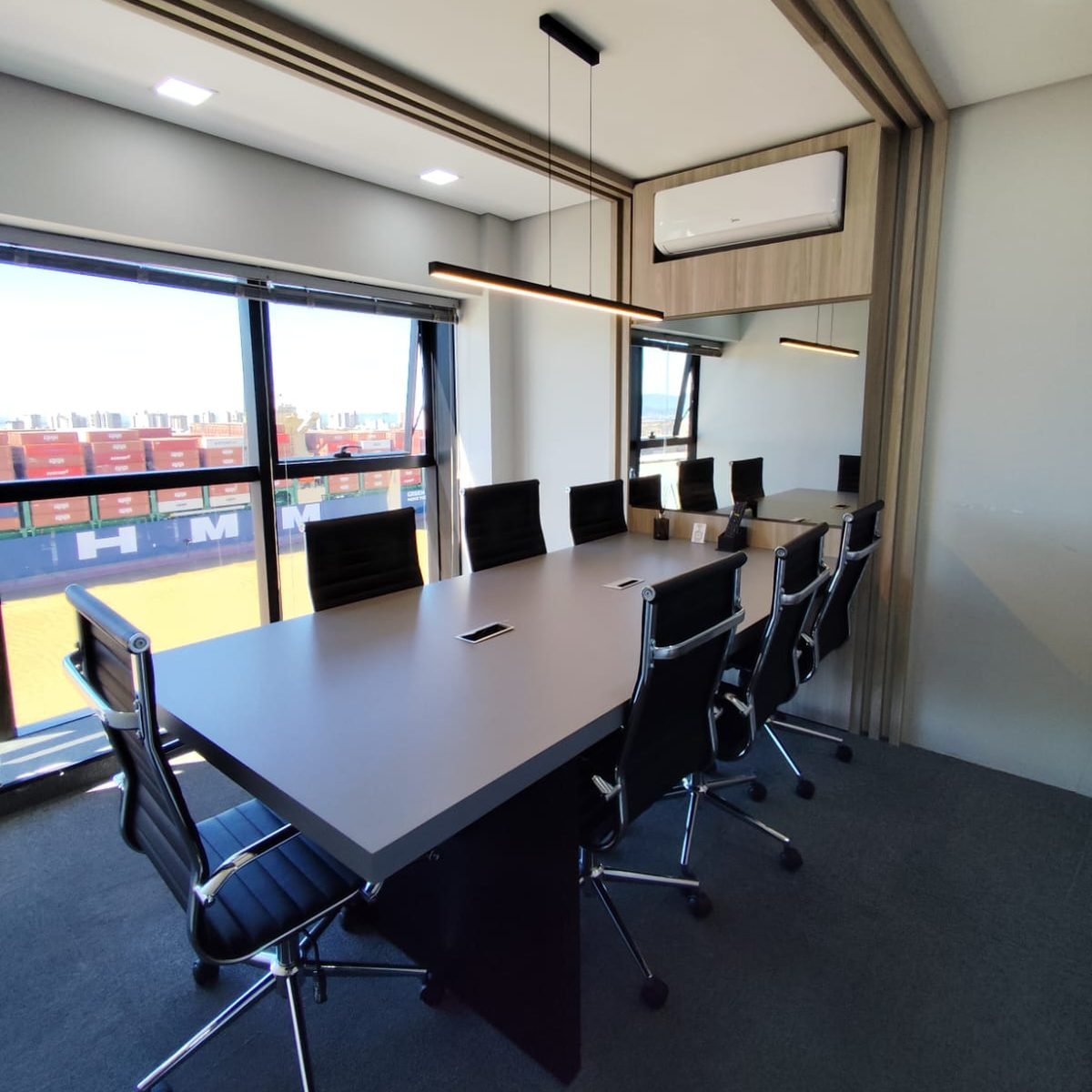 Sala de reuniões da unidade, com um navio porta-contêineres visível pela janela